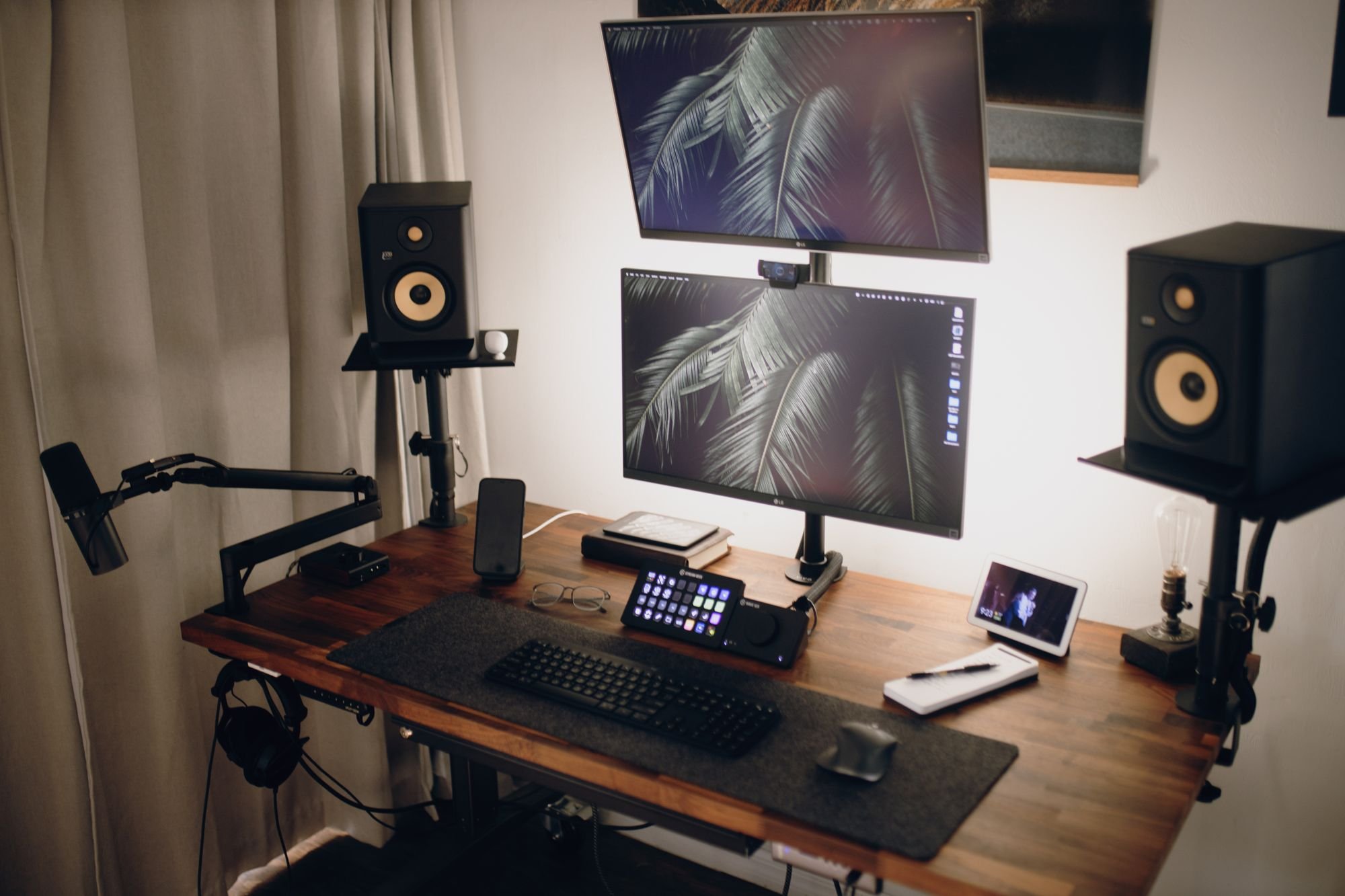 A streaming desk with two monitors, a microphone on an arm and speakers